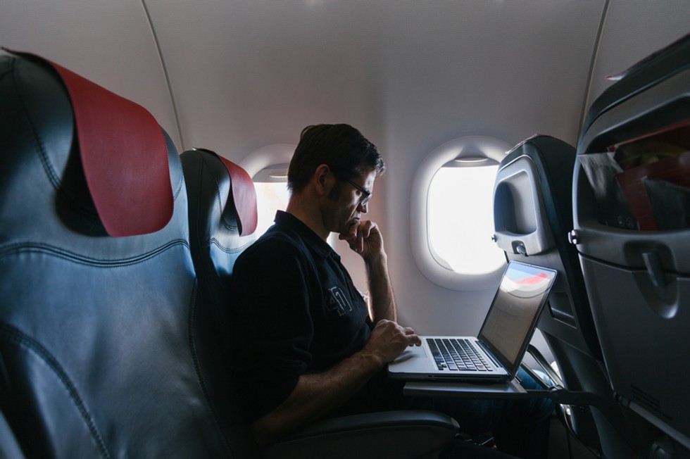 Empleado volando en el avión utilizando la aplicación Payhawk para calcular las emisiones de CO2 corporativas de la fase tres.